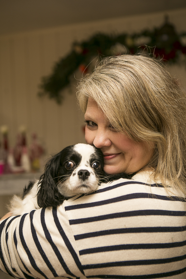 Cavalier King Charles spaniel snuggling on woman's shoulder