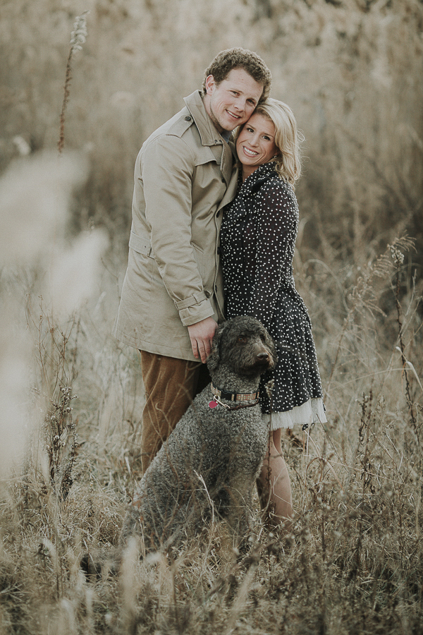 winter engagement photos with Labradoodle, woman wearing cute black coat with white flecks