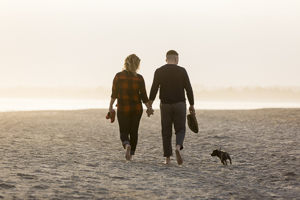 couple walking away with puppy running next to them engagement photos with puppy ideas