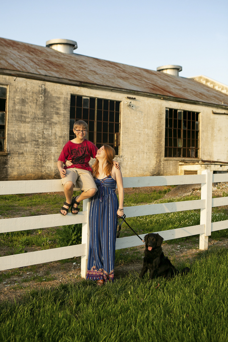 boy sitting on a fence, mom looking at him, puppy sitting on the ground, family portraits with pets, ©Mandy Whitley Photography