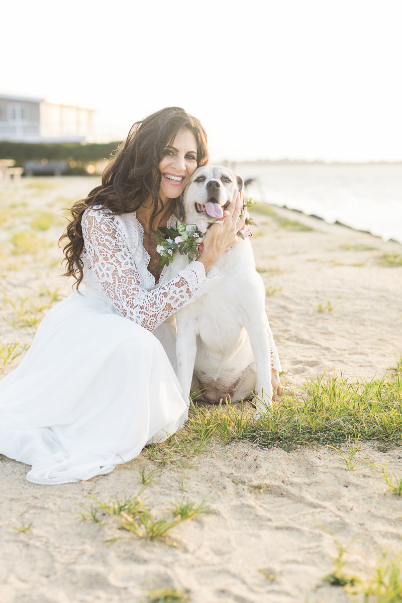 woman wearing long white dress cuddling with senior dog on the sand, NJ lifestyle pets and people photography | ©Kelly Sea Images 